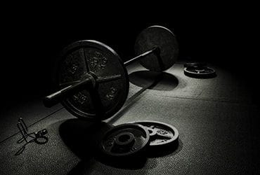Dark boxing gym floor with barbells and weights.